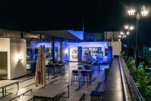 a rooftop patio with tables and chairs at night at CS Luxurio Presendential Suites Gachibowli in Hyderabad