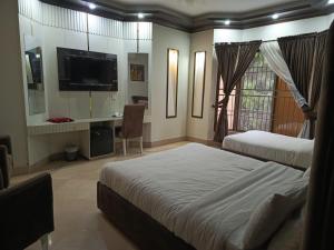a bedroom with two beds and a desk and a television at Sonnet Inn Guest House in Dargai