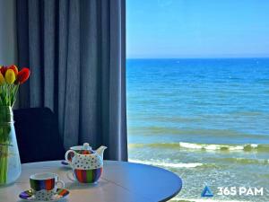 a table with a vase of flowers and a table with a view at 365PAM - Boulevard Z Widokiem Na Morze in Ustronie Morskie +108 photos