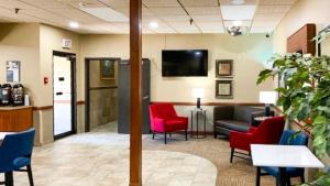 a waiting room at a hospital with red chairs and a couch at Motel 6 Minot, ND in Minot