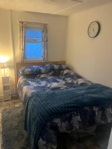 a bedroom with a bed and a clock on the wall at The Snug - All Seasons Chalet Breaks in Leysdown-on-Sea
