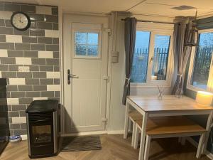 a room with a door and a table and a clock at The Snug - All Seasons Chalet Breaks in Leysdown-on-Sea