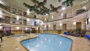 a large swimming pool in a large building with tables and chairs at Motel 6 Minot, ND in Minot