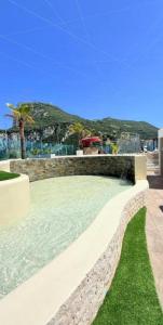 a swimming pool with a stone wall and green grass at Gibraltar Luxe Stay 1403 in Gibraltar