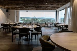 a restaurant with tables and chairs and large windows at Le Relais D'Orti in Sainte-Ode