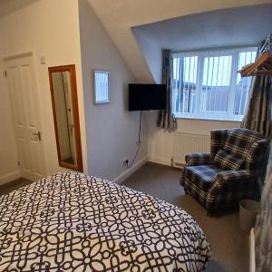 a bedroom with a bed and a chair and a television at Bagshaw Bed & Breakfast in Bridlington