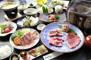 a table full of plates of food with meat and vegetables at Minshuku Asogen in Aso