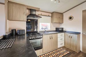 a kitchen with wooden cabinets and a stove top oven at Host & Stay - 10th Avenue in Morpeth