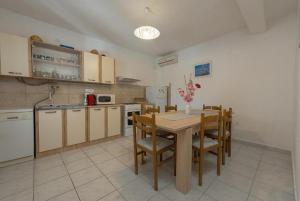 a kitchen with a wooden table and chairs and a kitchen with a refrigerator at Holiday Home Vala in Vinišće