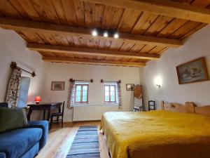 a bedroom with a yellow bed and a blue couch at Füstös Cottage Gömörszőlős in Gömörszőlős