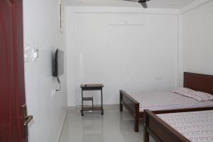 a room with two beds and a tv on the wall at Anand Classic in Thiruchendur
