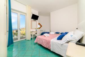 ein Schlafzimmer mit Bett, Schreibtisch und Balkon in der Unterkunft Hotel America in Marina di Camerota + 81 Fotos