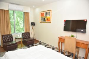 a hotel room with a bed and two chairs and a television at Luxury Stay Near Neelum River Valley,208 in Muzaffarabad