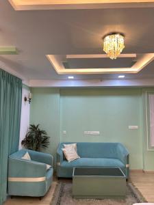 a living room with a blue couch and a chandelier at Piyush stay in Lucknow