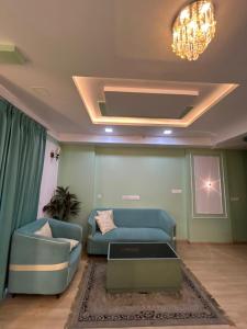 a living room with a blue couch and a chandelier at Piyush stay in Lucknow