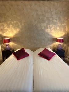 zwei Betten mit weißen Laken und roten Kissen in einem Schlafzimmer in der Unterkunft Hotel De Stern in Scheveningen