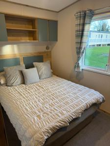 a bedroom with a large bed with a window at Coastal Caravan Seton Sands in Port Seton
