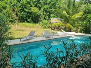 a swimming pool with two chairs and a umbrella at DG House in Thong Sala
