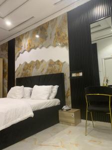 ein Schlafzimmer mit einem großen Bett und einem Stuhl in der Unterkunft ZAPHOMEs in Asaba