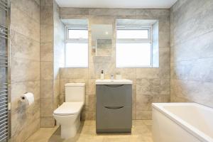 a bathroom with a toilet and a sink and a tub at Comfortable 3-BR House in Malvern Link