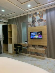 ein Schlafzimmer mit einem Fernseher an der Wand in der Unterkunft ZAPHOMEs in Asaba