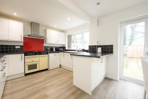 a kitchen with white cabinets and a large window at Comfortable 3-BR House in Malvern Link +16 photos