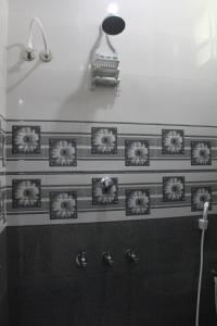 a bathroom with a shower with flowers on the wall at Anand Classic in Thiruchendur