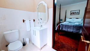 a bathroom with a toilet and a bed with a mirror at Casa da Maíssa in Ponta Delgada
