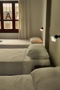 three beds in a room with a window at PASEO GüEMES HOTEL in Salta