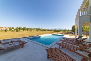 a swimming pool on a patio with two wooden benches at Villa Green Oasis in Lovreć