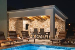 a patio with chairs and a swimming pool at night at Villa Green Oasis in Lovreć