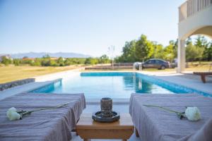two tables with flowers on them next to a swimming pool at Villa Green Oasis in Lovreć
