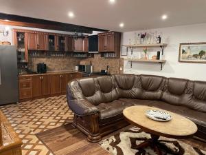 a living room with a leather couch and a table at Ádi Vendégház - Bekecs in Bekecs