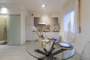 a living room with a glass table and a kitchen at Casetta in Via Dini in Padova