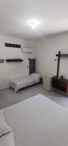 a white room with two beds and a rug at Verde & Sal 11 in Ilhéus