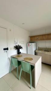 a kitchen with a table and two green chairs at Studio V Ininga in Teresina