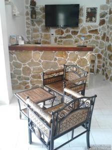 two benches sitting in front of a stone wall at Angelika in Alinda