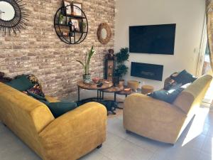 a living room with two couches and a brick wall at Chambre chaleureuse in Grosley-sur-Risle