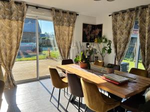 a dining room table with chairs and a large window at Chambre chaleureuse in Grosley-sur-Risle