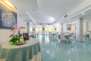 ein Esszimmer mit einem Tisch und einer Vase mit Blumen in der Unterkunft Hotel America in Marina di Camerota