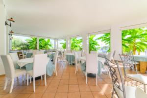 ein Restaurant mit weißen Tischen und Stühlen und Fenstern in der Unterkunft Hotel America in Marina di Camerota