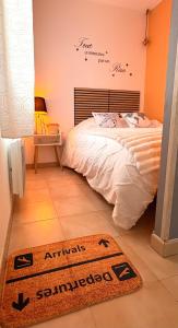 a bedroom with a bed and a welcome mat on the floor at Aéroport à pied, Escale 25 in Tillé