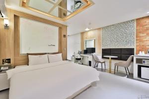 a bedroom with a large white bed and a kitchen at Time Hotel in Yangsan