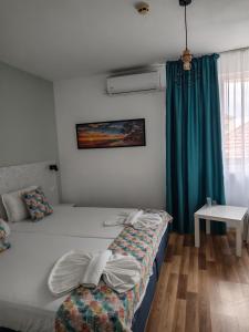 a bedroom with two beds and a blue curtain at Chance Sarafovo in Burgas