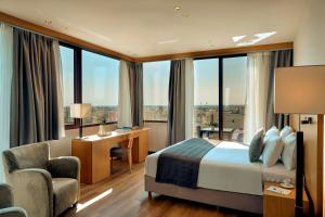 a hotel room with a bed and a chair and windows at Zeus Thessaloniki Lazart in Thessaloniki