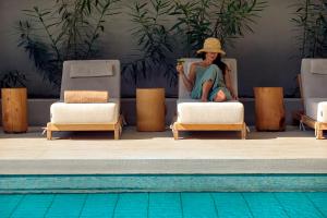 a woman sitting in a chair next to a pool at Zeus Thessaloniki Lazart in Thessaloniki