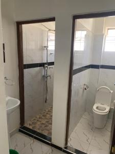 a bathroom with a toilet and a glass shower at Kisumu gateway 2br in Kisumu