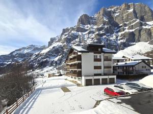 a building with cars parked in front of a mountain at Panorama 20, Grosses Studio, Nahe Ski-Pisten, Parkplatz in Leukerbad