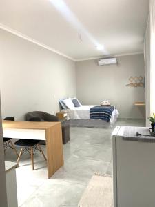 a room with a bed and a desk and a table at Studio Aconchegante e Moderno in Castanhal