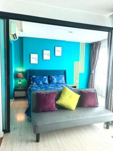 a blue bedroom with a bed with purple and yellow pillows at Centrio phuket 07 in Ban Rangeng